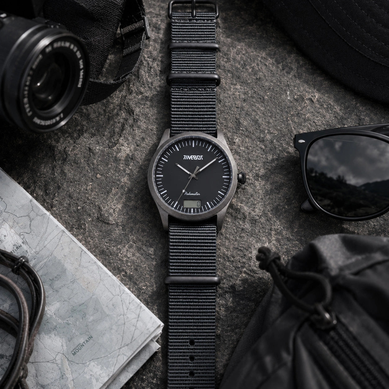 Timebot T591C1 watch styled on a grey workspace desk next to a camera, reading glasses, and map.