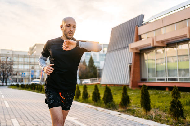 Man running outdoors who is checking his steps on a timebot pedometer watch