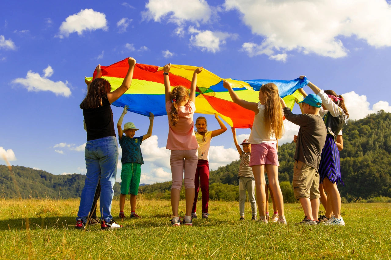 Group of children holding a colorful umbrella in a grassy field with a blue sky, wearing timebot sport watches 